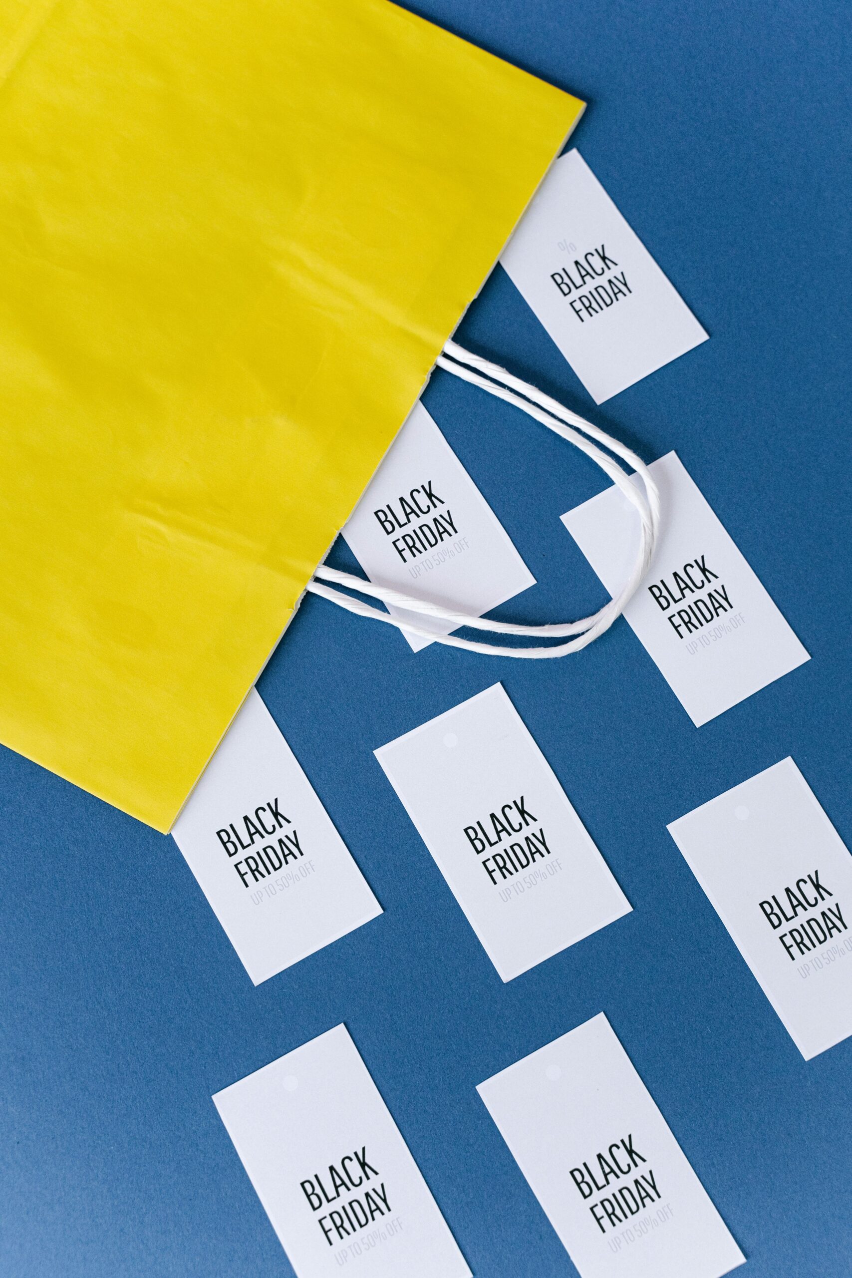 Flat lay of a yellow shopping bag with Black Friday cards on a blue background.